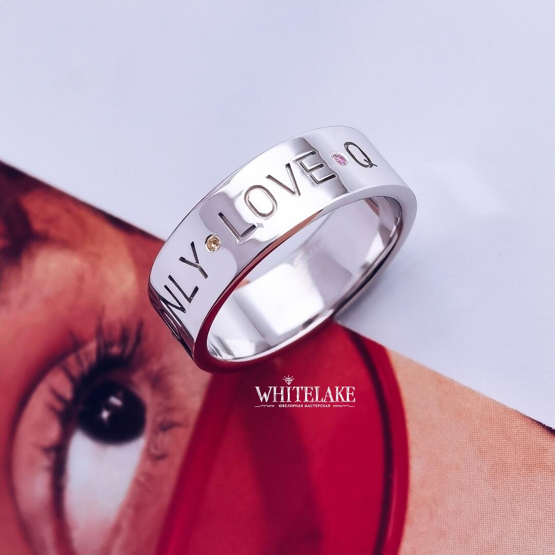 Кастомное кольцо с гравировкой Only love, изготовленное из серебра, украшенное цитринами и розовыми сапфирами, лежащее боком на картинке
